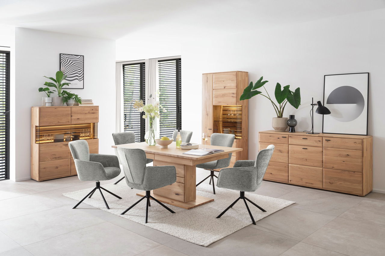 Linea Natura Sideboard GEORGIA Modernes Wohnzimmer mit einem Sideboard aus Holz, umgeben von stilvollen grauen Stühlen und einem Holztisch, aus der Perspektive des Raumes betrachtet.
