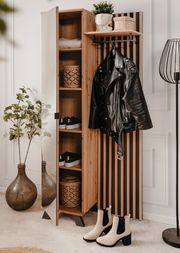 Garderobe aus Holz mit Spiegel, Regalen und Haken, frontal fotografiert. Dekoriert mit Pflanzen, Körben und Kleidung.