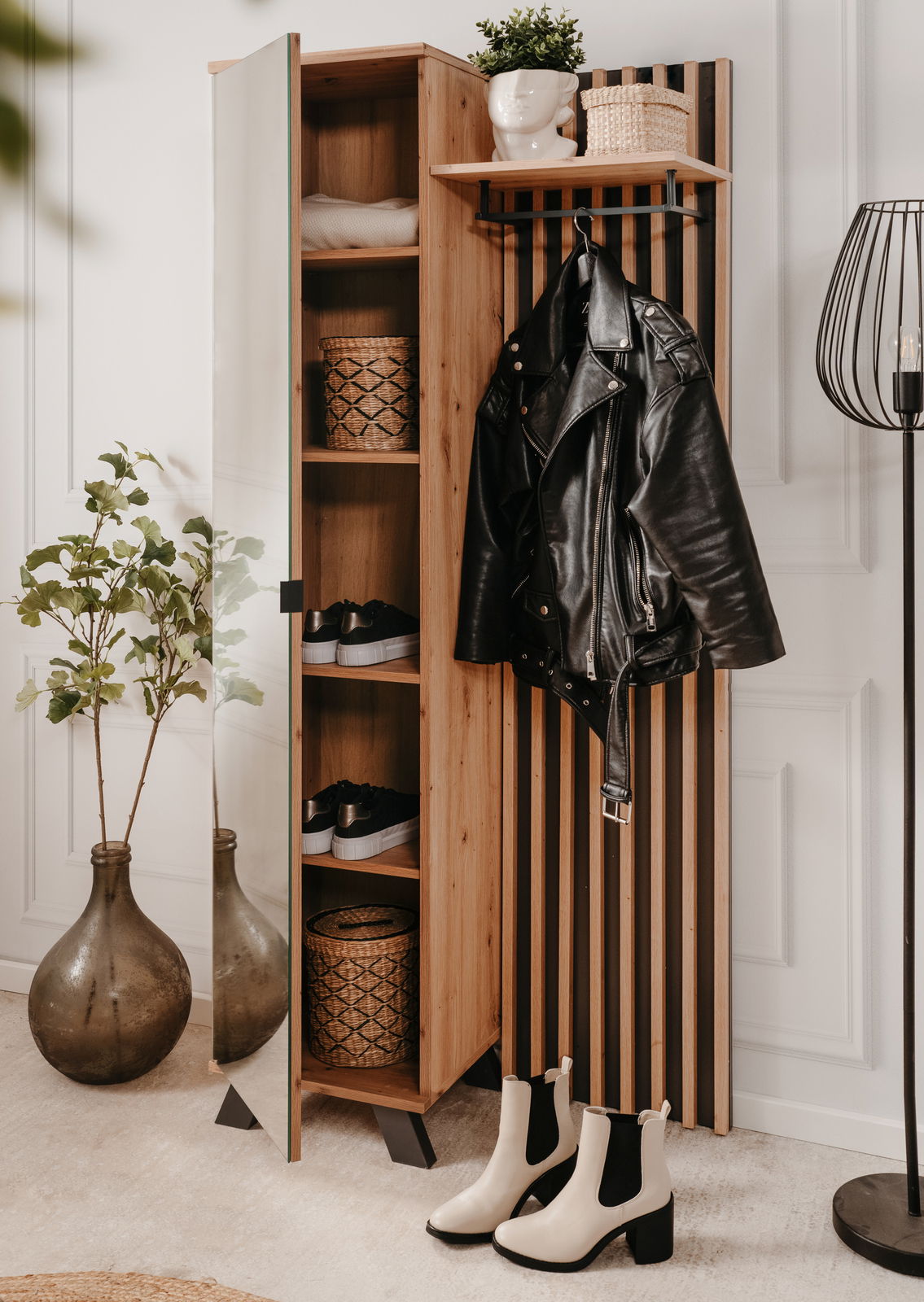 Garderobe aus Holz mit Spiegel, Regalen und Haken, frontal fotografiert. Dekoriert mit Pflanzen, Körben und Kleidung.