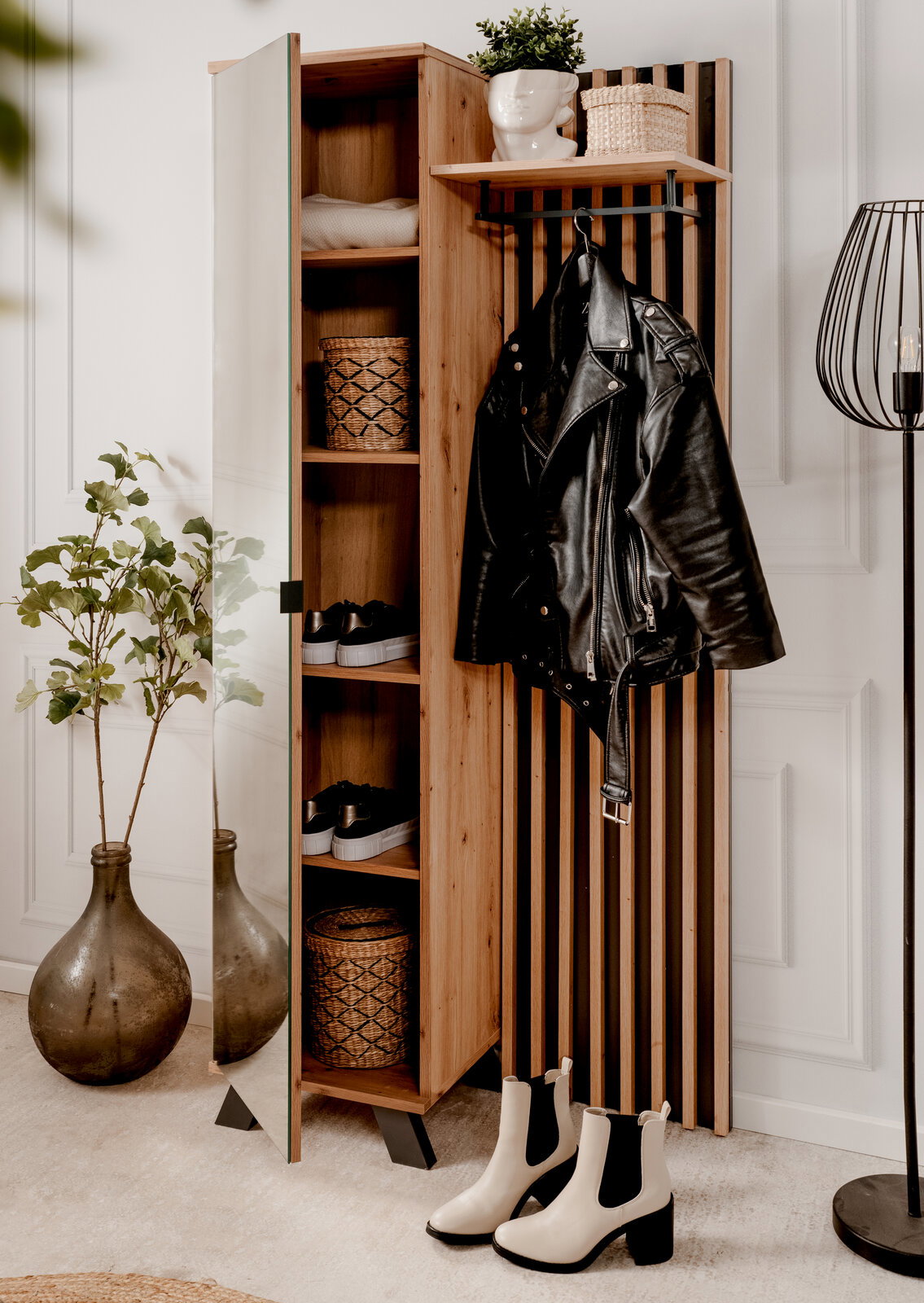 Garderobe aus Holz mit Spiegel, Regalen und Haken, frontal fotografiert. Dekoriert mit Pflanzen, Körben und Kleidung.