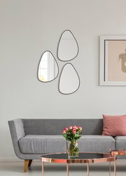 Drei organisch geformte Wandspiegel in einem modernen Wohnzimmer, Perspektive von vorne.