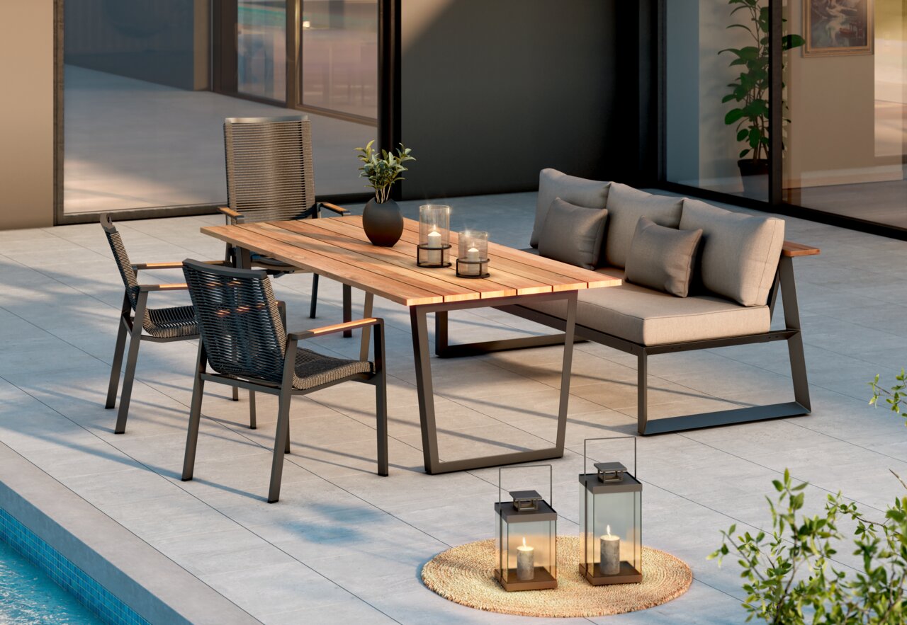 Amatio Select Stapelsessel LA SPEZIA Moderne Outdoor-Loungegruppe auf einer Terrasse am Pool: rechteckiger Holztisch mit dunklem Metallgestell, zwei Seilstühle und ein graues 2-Sitzer-Sofa mit Kissen, dekoriert mit Kerzen und Pflanze, aufgenommen in schräger Frontansicht.