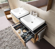 Moderne Badkombination mit zwei weißen Waschbecken, Holzunterschränken und geöffneter Schublade, aus der Vogelperspektive.