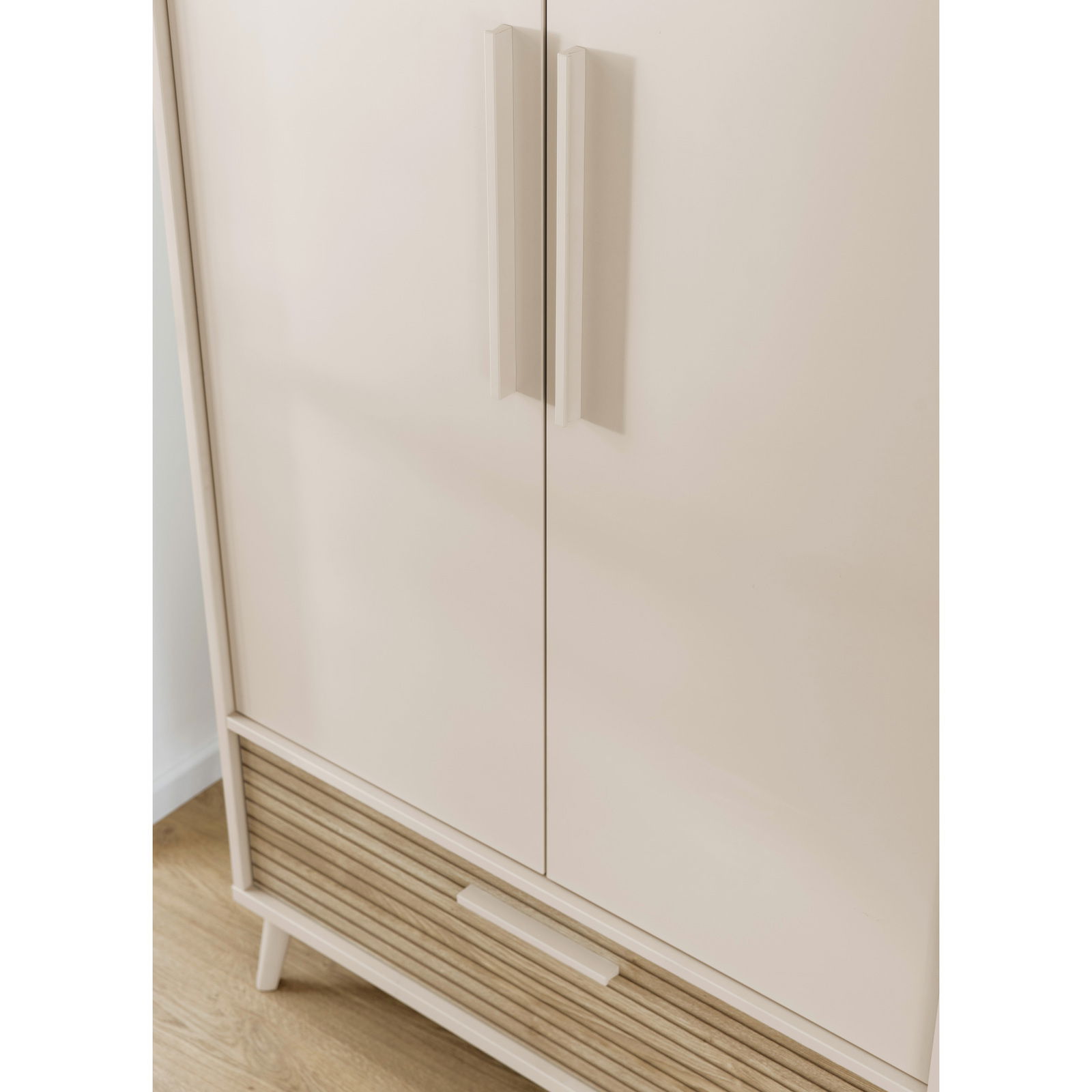 Nahaufnahme eines modernen Kleiderschranks mit zwei Türen und einer Schublade, in heller Farbe mit Holzdetails, aus der Vorderansicht.