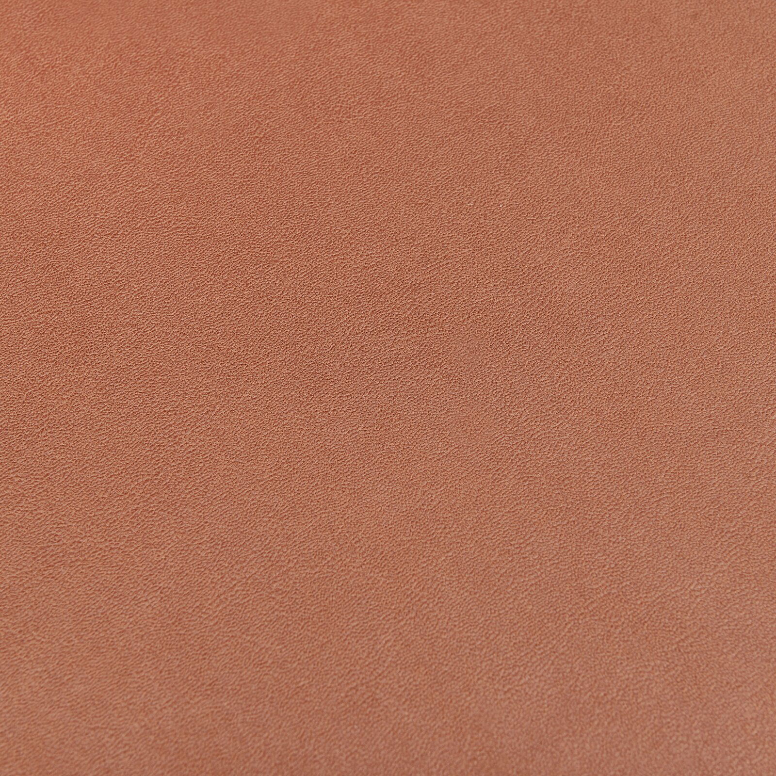 Nahaufnahme einer orangefarbenen, strukturierten Oberfläche eines Stuhlsitzes.