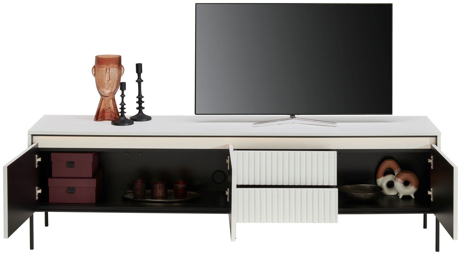 Hom´in TV-Lowboard NOTO Frontale Ansicht eines modernen TV-Lowboards mit offenen Türen, dekoriert mit Kerzenhaltern und einer Skulptur, sowie einem Fernseher darauf.