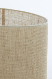 Nahaufnahme eines ovalen, geraden Lampenschirms aus beigem Stoff mit feiner Textur, seitliche Perspektive