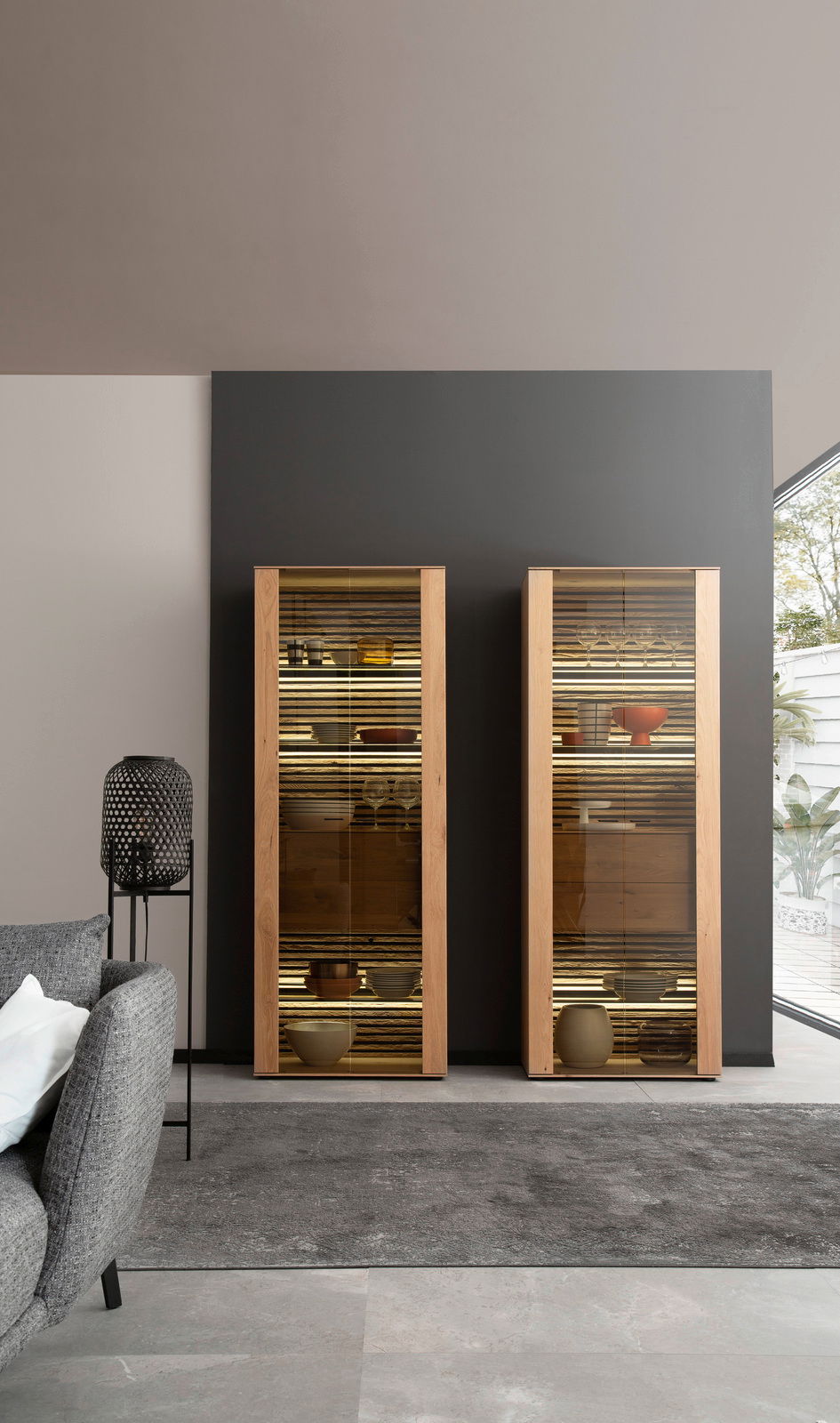 Zwei moderne Vitrinen aus Holz mit Glastüren, frontal fotografiert, gefüllt mit dekorativen Objekten, in einem stilvollen Wohnzimmer.