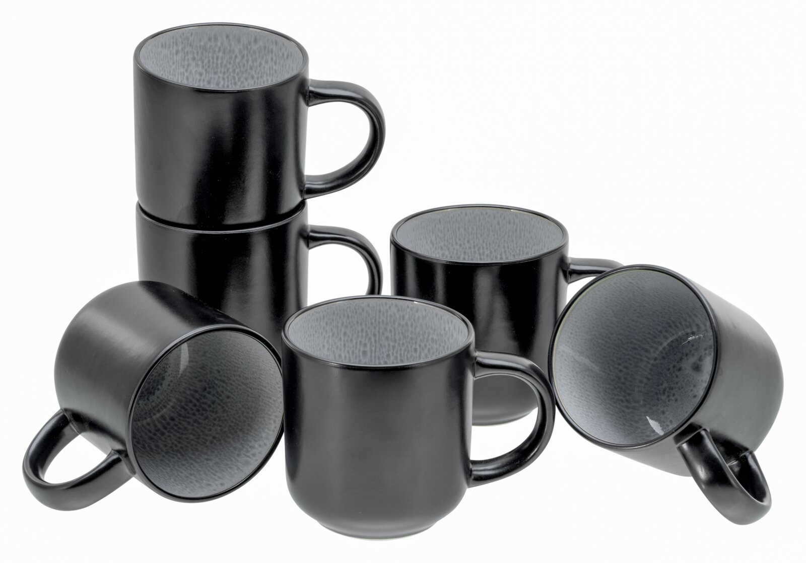 Sechs schwarze Keramik-Kaffeebecher mit grauer, strukturierter Innenlasur, teils gestapelt und teils liegend, fotografiert in schräger Frontansicht vor weißem Hintergrund