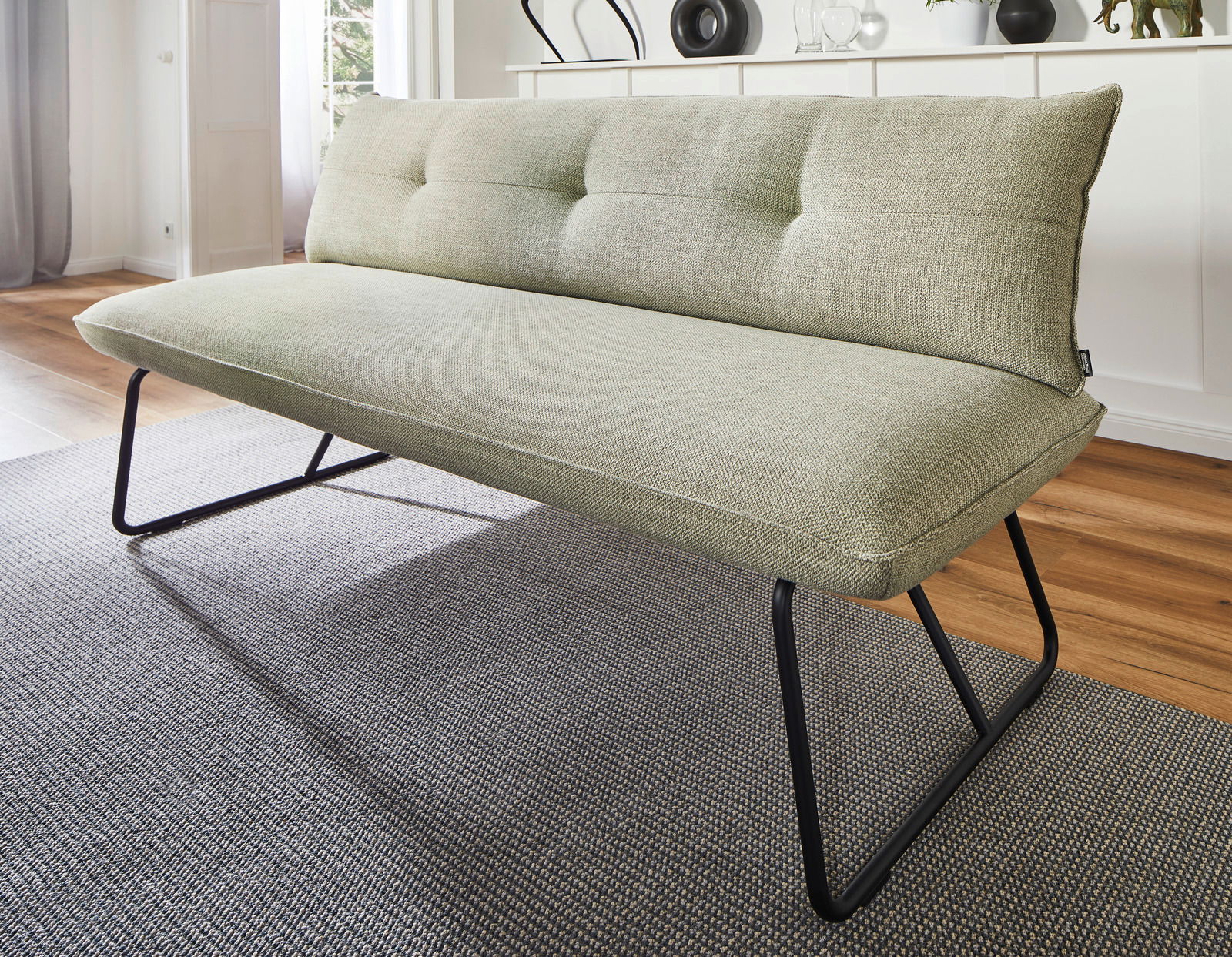 Grüne Polsterbank mit schwarzem Metallgestell, seitliche Perspektive