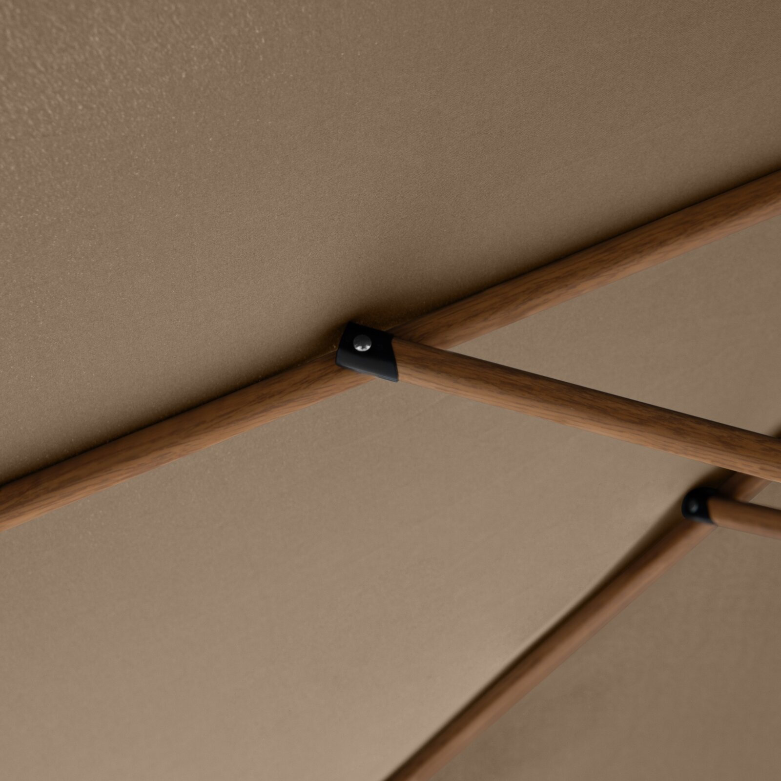 Detailaufnahme von unten: Holzstreben mit schwarzem Metallverbinder unter einer beigefarbenen Tischplatte