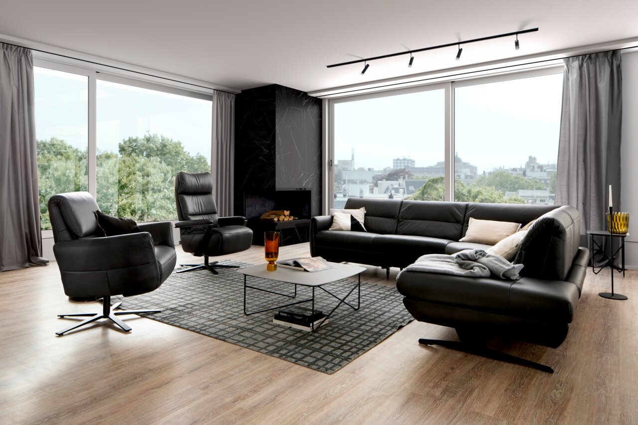 Moderne Eckgarnitur in einem stilvollen Wohnzimmer mit großen Fenstern und Blick auf die Stadt, Perspektive von vorne.