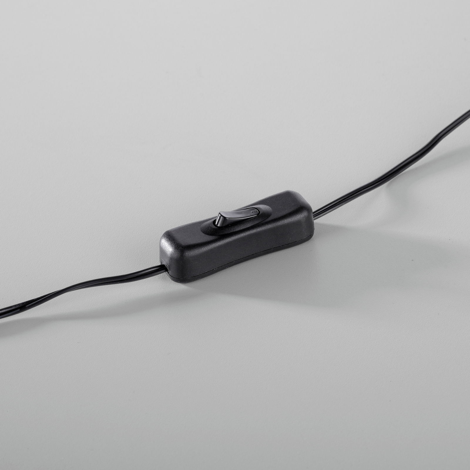 Nahaufnahme eines schwarzen Kippschalters an einem Kabel, perspektivisch von oben fotografiert.