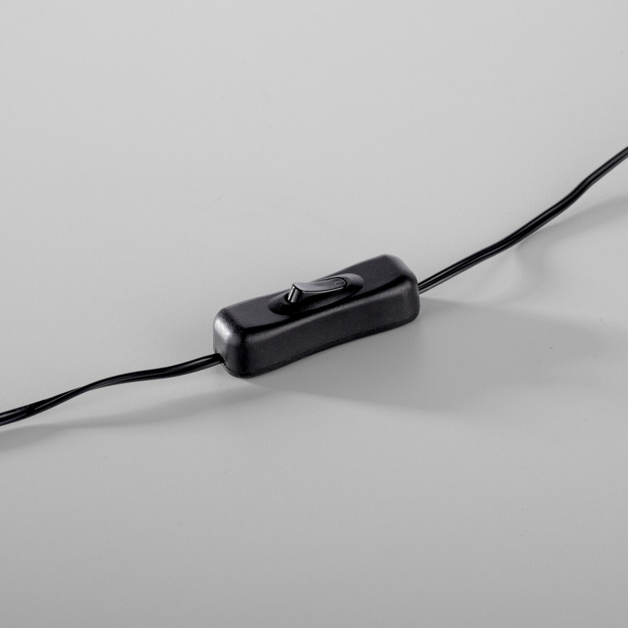 Nahaufnahme eines schwarzen Kippschalters an einem Kabel, perspektivisch von oben fotografiert.