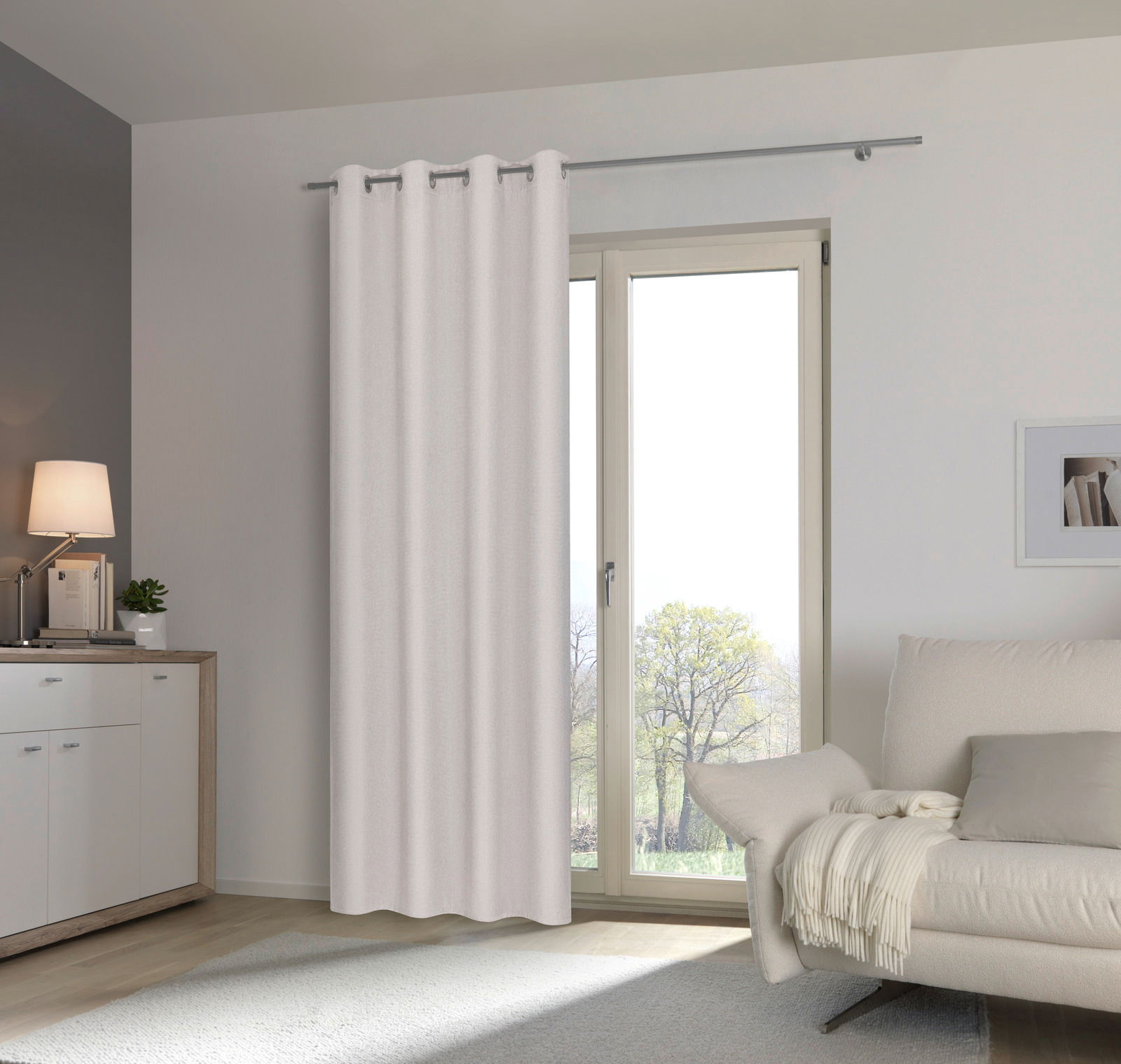 Heller Ösenschal vor einem Fenster in einem modernen Wohnzimmer, seitliche Perspektive