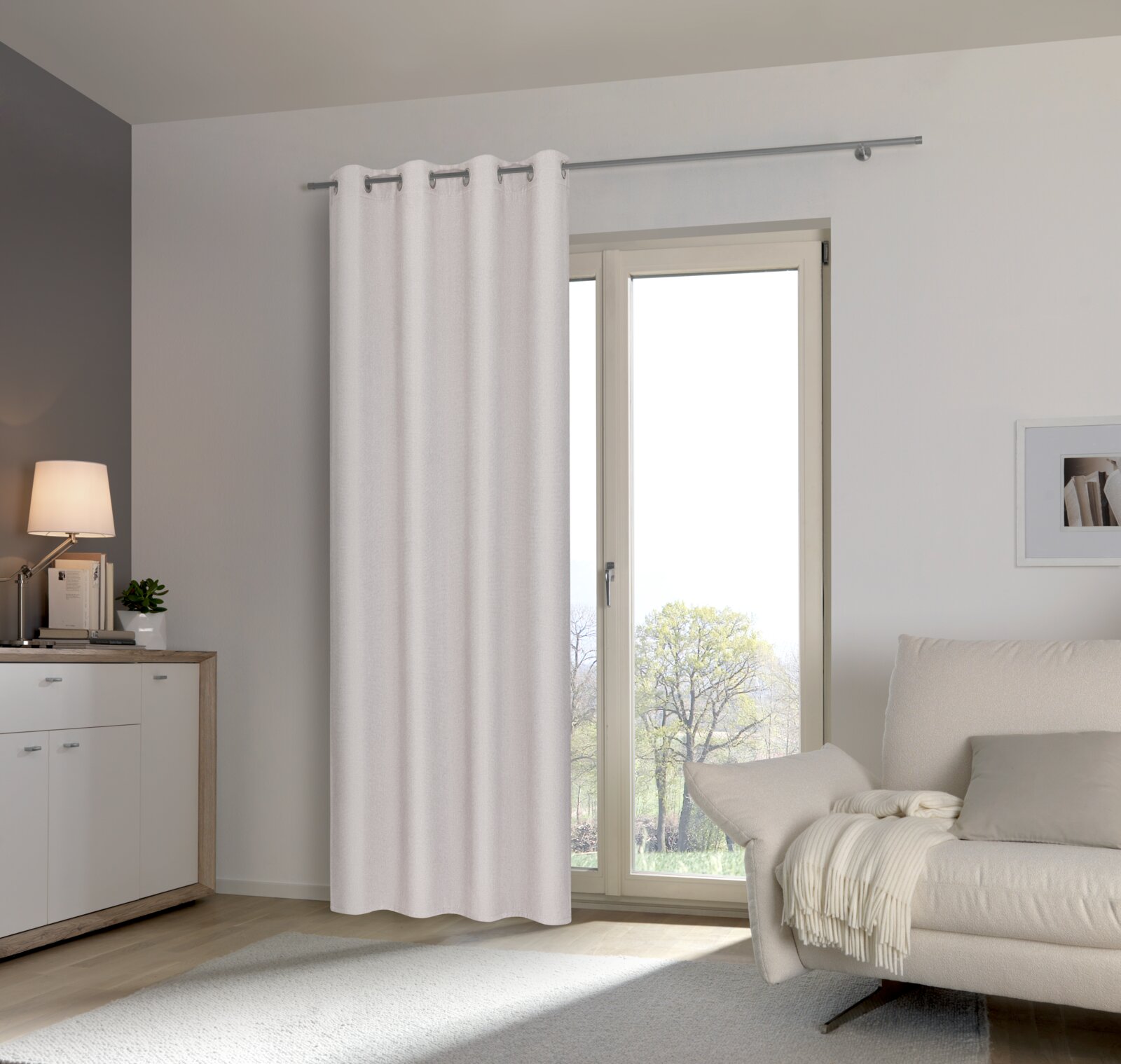 Heller Ösenschal vor einem Fenster in einem modernen Wohnzimmer, seitliche Perspektive