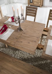 Holzesstisch mit ausziehbarer Funktion, gedeckt mit Kerzenleuchter und Geschirr, aus der Vogelperspektive fotografiert.