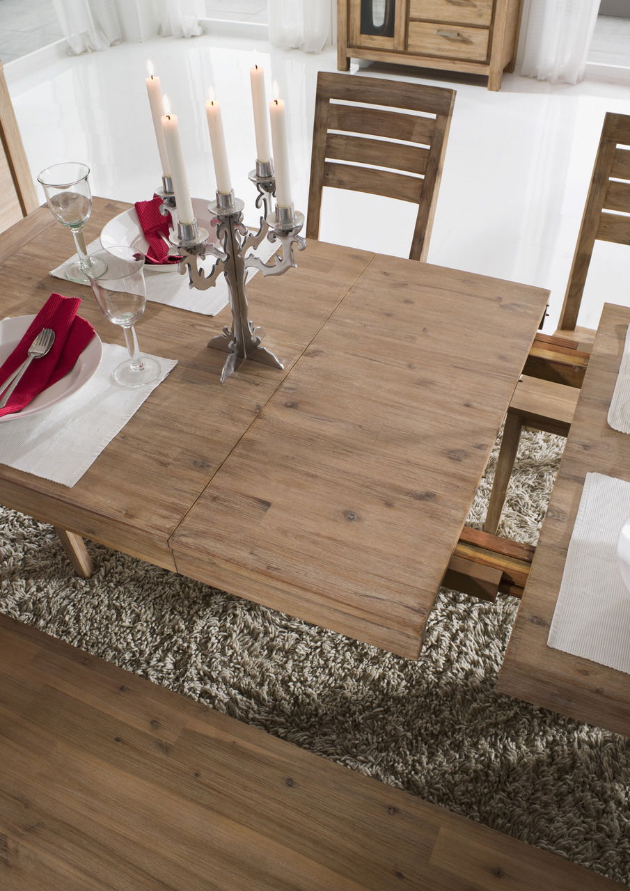 Holzesstisch mit ausziehbarer Funktion, gedeckt mit Kerzenleuchter und Geschirr, aus der Vogelperspektive fotografiert.