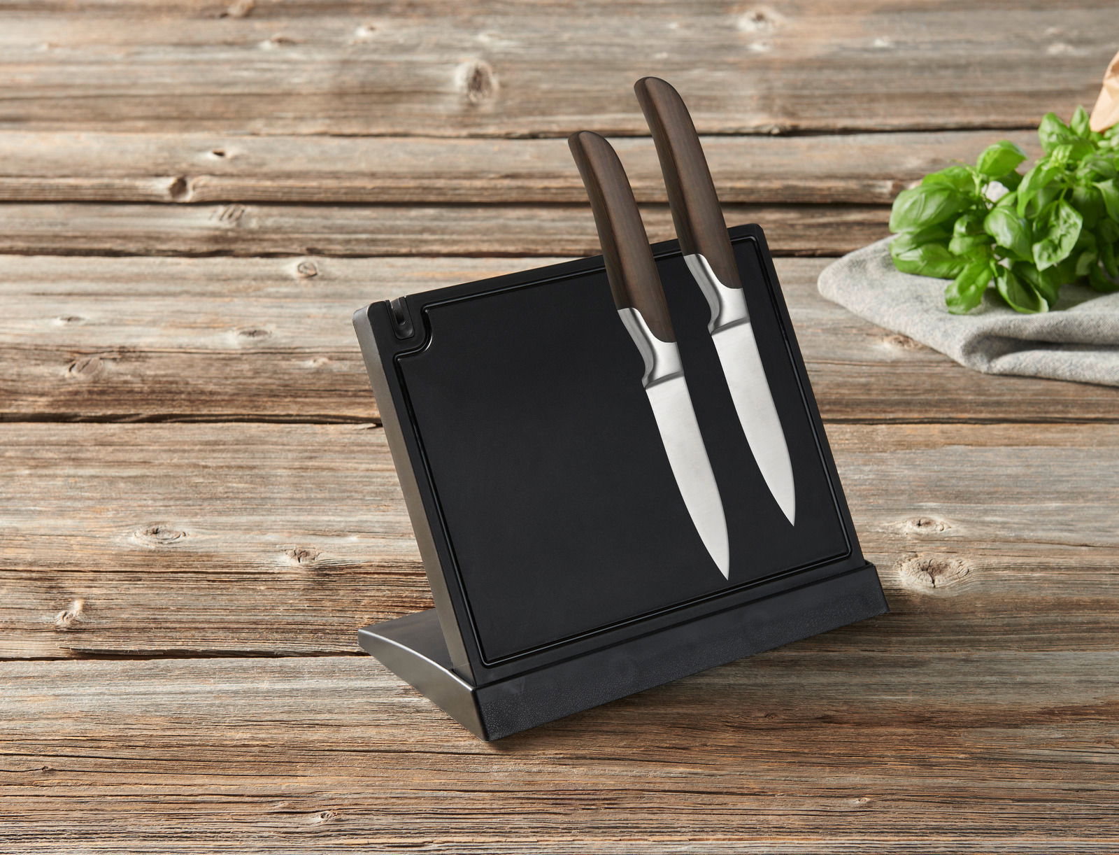 Moderner Messerblock mit zwei Messern, seitliche Perspektive, auf einem Holztisch platziert.