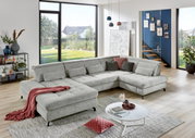 Graue Polsterrundecke in modernem Wohnzimmer mit großen Fenstern, dekoriert mit Kissen und Decke, seitliche Perspektive.