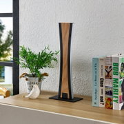 Moderne Tischlampe mit schlankem, geometrischem Design in Holzoptik und schwarzem Rahmen auf Sideboard neben Büchern und Pflanze, Frontansicht