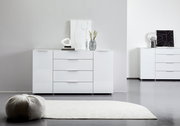 Weißes Sideboard mit drei Schubladen und zwei Türen, dekoriert mit modernen Accessoires, aus frontaler Perspektive fotografiert.