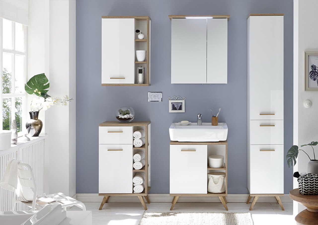 Moderne badkamermeubels in wit en houtlook, bestaande uit een wandkast, een wastafelonderkast en een hoge kast, gefotografeerd vanaf de voorkant.