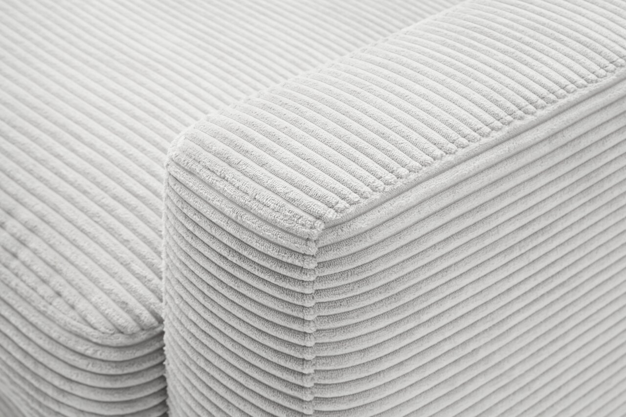 Nahaufnahme einer hellgrauen, gerippten Stoffoberfläche eines Longchairs, perspektivisch von oben fotografiert.