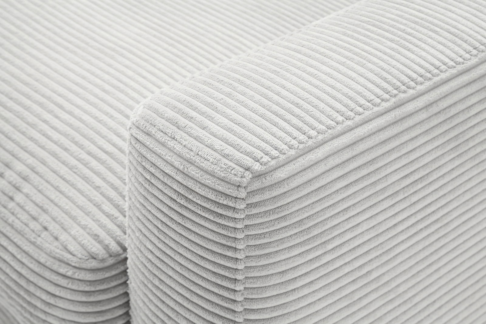 Nahaufnahme einer hellgrauen, gerippten Stoffoberfläche eines Longchairs, perspektivisch von oben fotografiert.