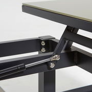 Nahaufnahme eines Loungetischs mit Metallgestell und Hebemechanismus, seitliche Perspektive.