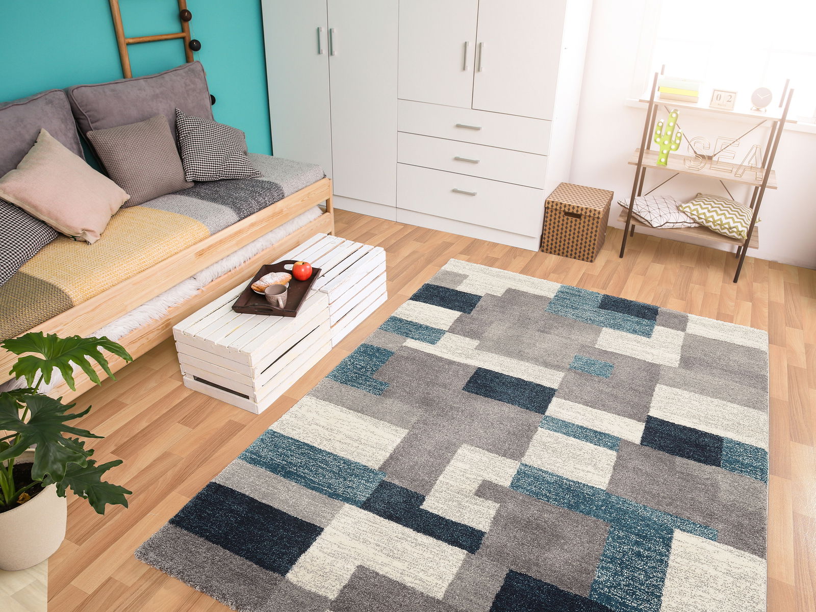 OCI Frisé-Teppich STEADY Moderner Frisé-Teppich in geometrischem Design mit Grautönen und Blautönen, in einem hellen Wohnzimmer mit Holzboden, Sofa und Dekorationen, aus der Vogelperspektive betrachtet.