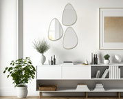 Drei moderne, organisch geformte Spiegel mit schmalem Rahmen an einer weißen Wand, perspektivisch von vorne betrachtet, über einem stilvollen Sideboard mit Dekorationen.