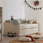Kinderzimmer mit beigem Tagesbett mit Ausziehbett und Schubladen, dekoriert mit Kissen und Stofftieren, seitliche Perspektive