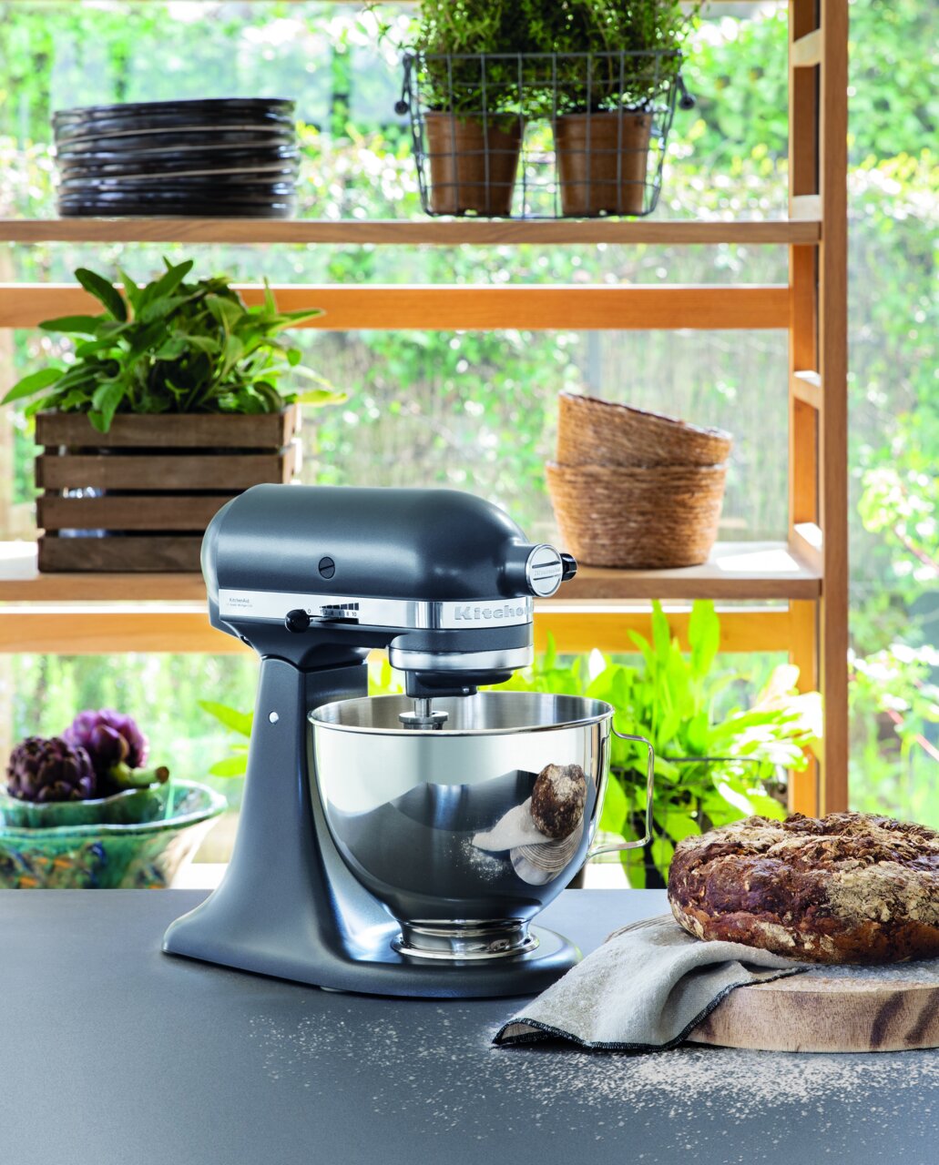 Küchenmaschine 4,3l in einer modernen Küche, seitliche Perspektive, mit frischem Brot und Pflanzen im Hintergrund.