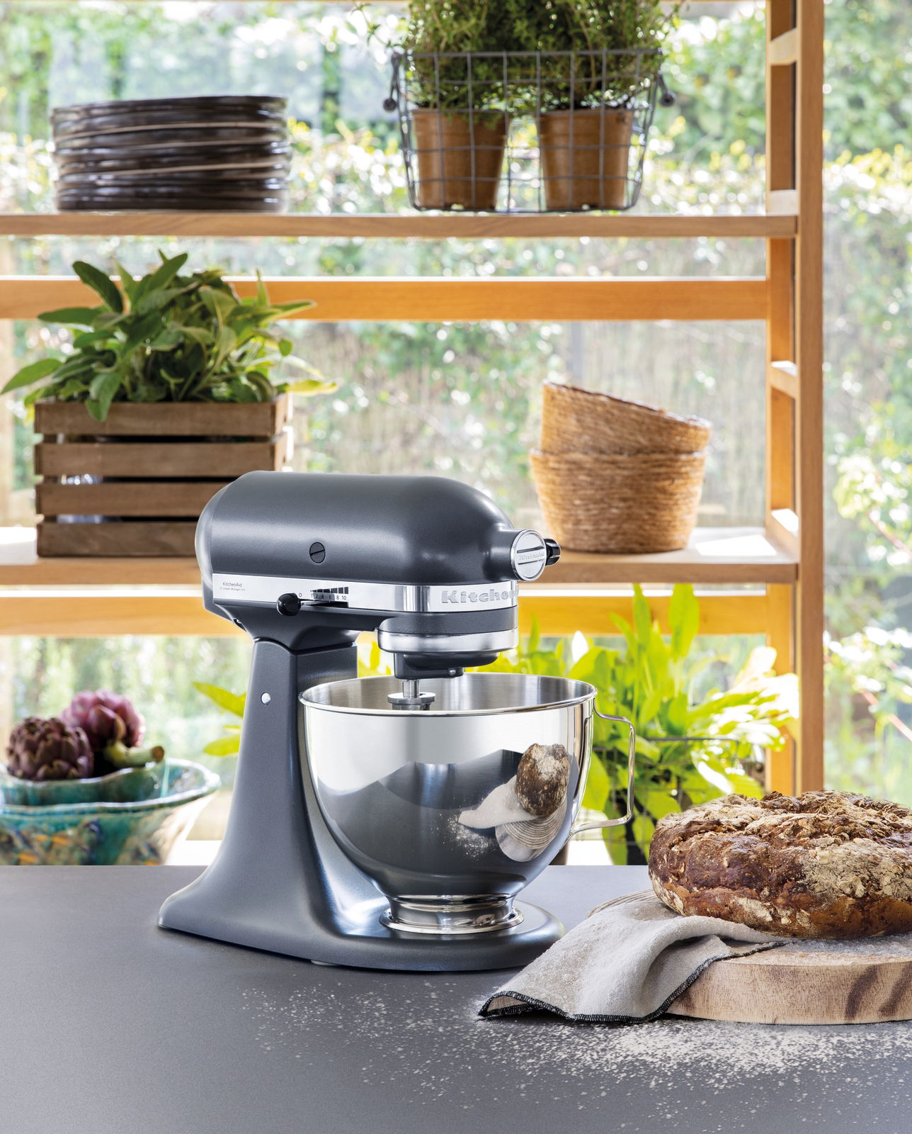 Küchenmaschine 4,3l in einer modernen Küche, seitliche Perspektive, mit frischem Brot und Pflanzen im Hintergrund.