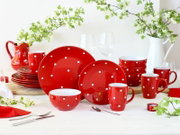 Rotes Geschirr-Set mit weißen Punkten (Teller, Schalen, Tassen und Krug) dekorativ auf einem Tisch arrangiert, frontale Perspektive auf die Produkte