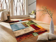 Moderner Teppich mit buntem geometrischem Muster in einem hellen Wohnzimmer, Perspektive von schräg oben.