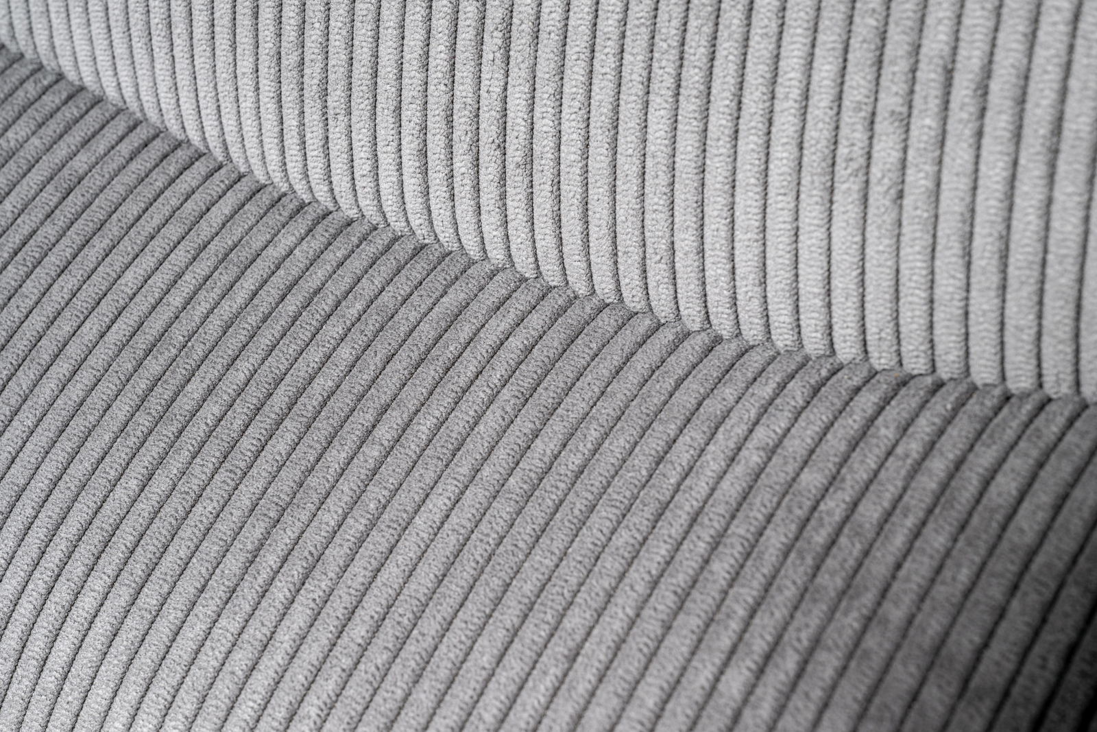 Nahaufnahme eines grauen, gerippten Stoffes eines Drehstuhlsitzes, von oben betrachtet.