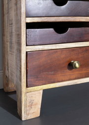 Nahaufnahme eines Sideboards aus Holz mit mehreren Schubladen, die aus verschiedenen Holzarten gefertigt sind. Die Perspektive zeigt die linke Seite des Möbels.