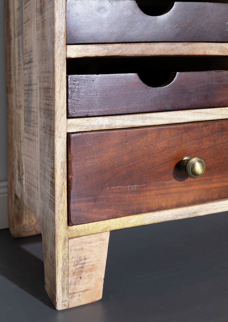 Close-up van een houten dressoir met meerdere lades, vervaardigd uit verschillende houtsoorten. Het perspectief toont de linkerkant van het meubelstuk.