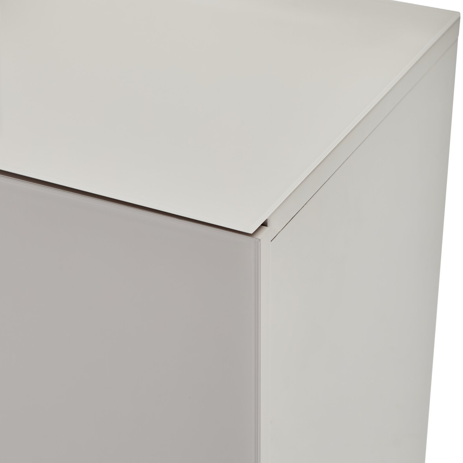Detailaufnahme eines weißen, minimalistischen Schrankmöbels mit glatter Oberfläche, aus leicht schräger Perspektive von oben auf die Ecke