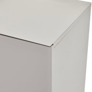 Detailaufnahme eines weißen, minimalistischen Schrankmöbels mit glatter Oberfläche, aus leicht schräger Perspektive von oben auf die Ecke