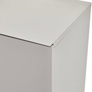 Detailaufnahme eines weißen, minimalistischen Schrankmöbels mit glatter Oberfläche, aus leicht schräger Perspektive von oben auf die Ecke
