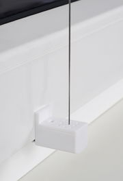 Nahaufnahme eines weißen Plissee-Halters mit gefädeltem Draht, montiert an einem Fensterrahmen.