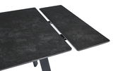Nahaufnahme eines ausziehbaren Esstisches mit dunkler, steinartiger Oberfläche und Metallmechanismus.