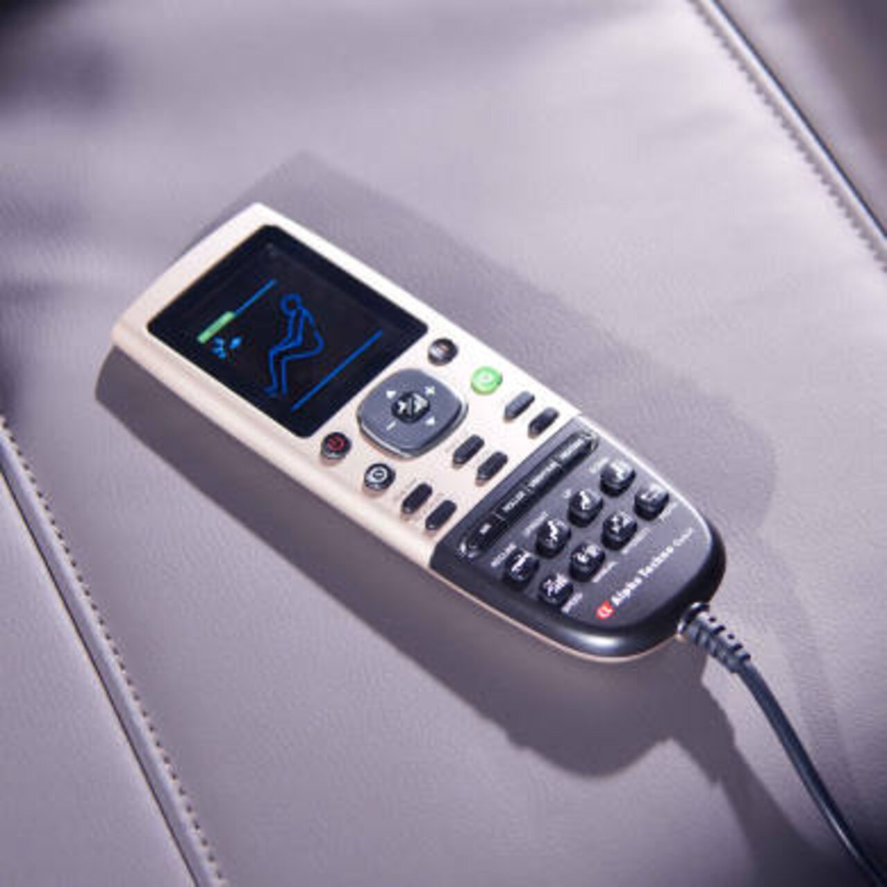Fernbedienung eines Massagesessels auf einer Lederoberfläche, von oben fotografiert.