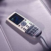 Fernbedienung eines Massagesessels auf einer Lederoberfläche, von oben fotografiert.