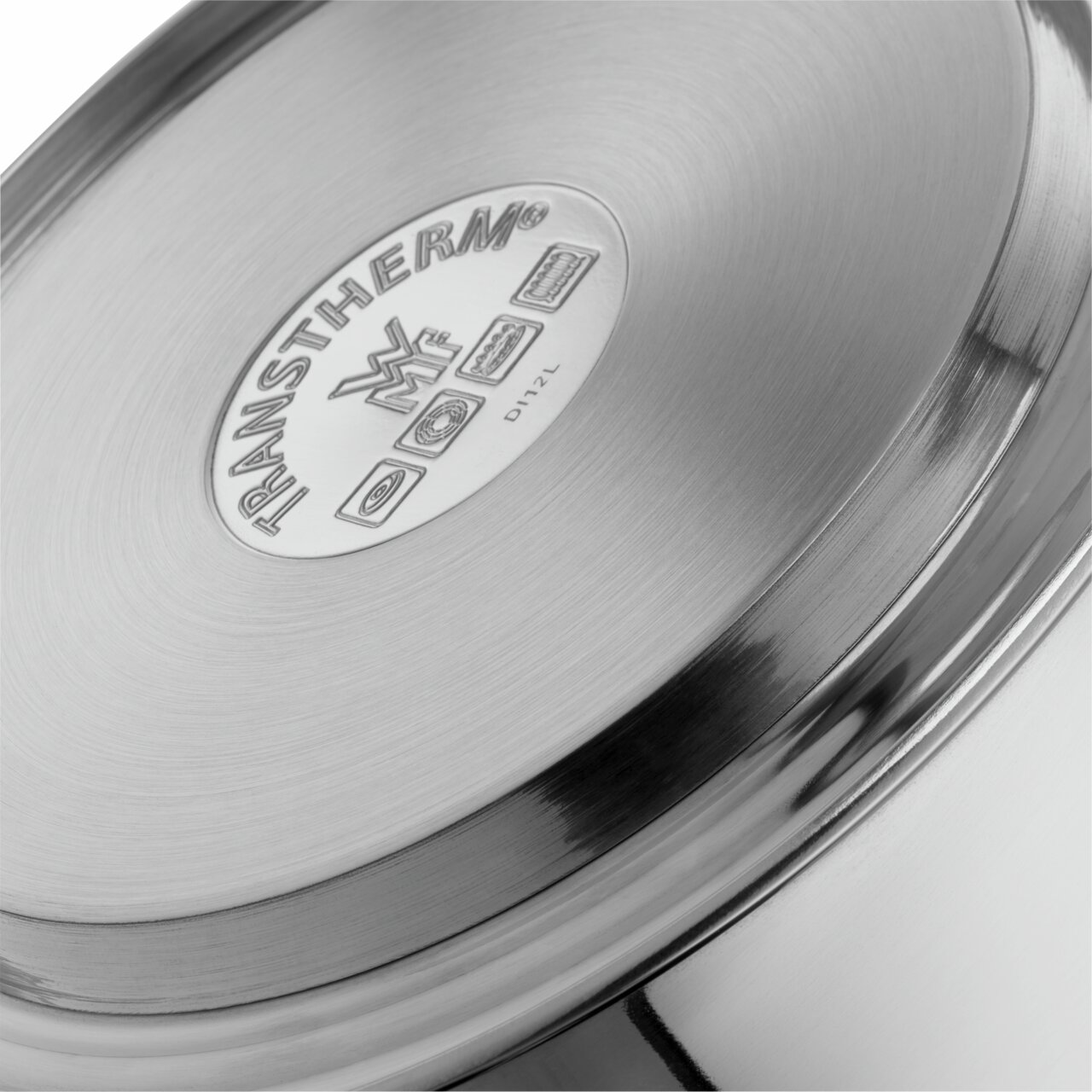 Nahaufnahme des Bodens eines Edelstahl-Flötenkessels mit TransTherm-Logo und Symbolen für verschiedene Herdarten.