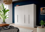 Moderner weißer Kleiderschrank mit fünf Türen und langen schwarzen Griffen in einem Schlafzimmer vor dunkelblauer Wand, perspektivische Frontansicht leicht von links