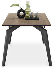 Moderner Esstisch mit Holzplatte und schwarzen Metallbeinen, dekoriert mit einer Vase und Gläsern, aus der Vorderansicht.